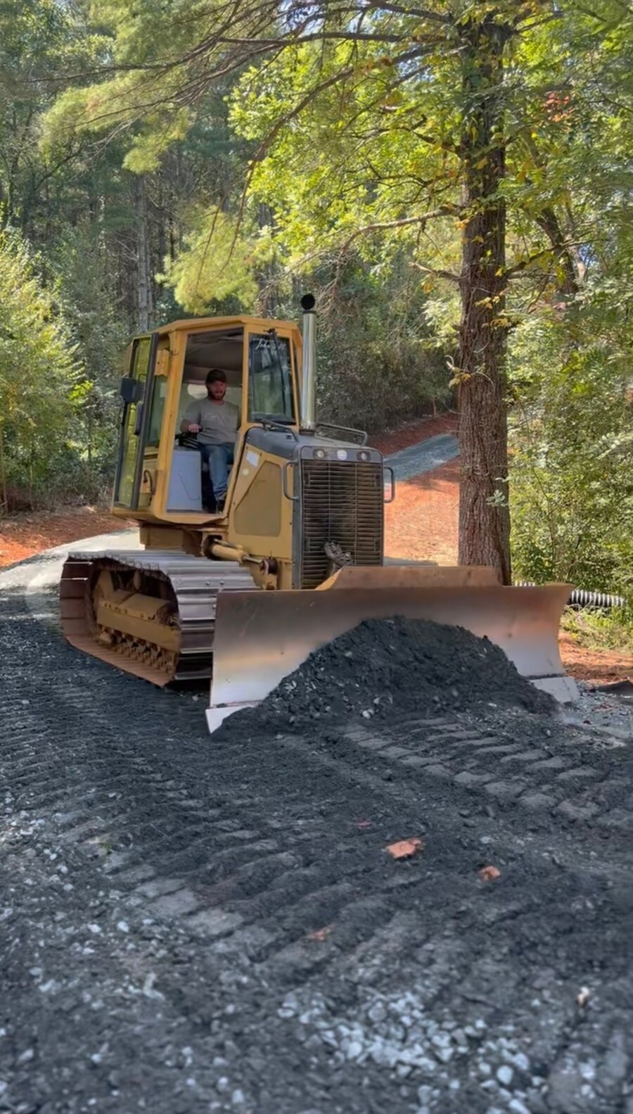 Ethan Tucker operating his bulldozer, pushing fresh gravel along a wooded mountain driveway