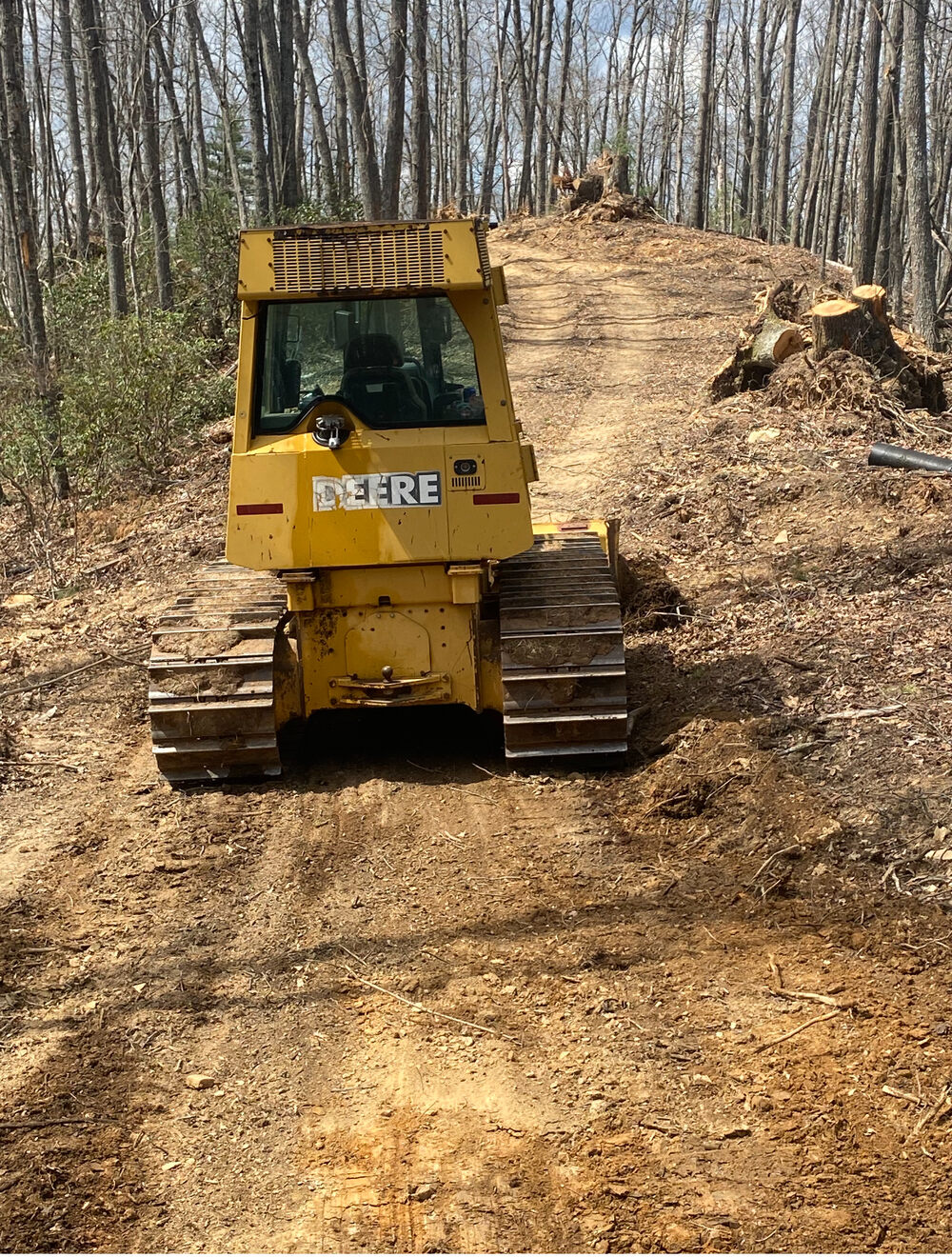 A bulldozer climbing a freshly cut grade on a mountain job site